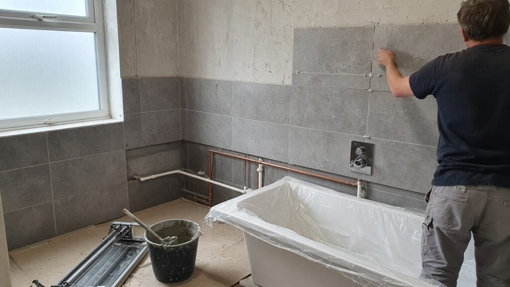 Bathroom mid-renovation with new tiling, exposed pipework and a bath awaiting fitting in a Croydon home